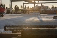 construction equipment and equipment sit in a warehouse in the sunlight in the background is a large crane