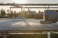 construction equipment and equipment sit in a warehouse in the sunlight in the background is a large crane