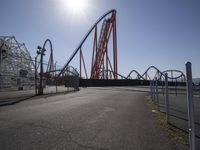 a roller coaster and an airplane going by at a theme park setting with a bright sun