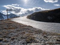 a long paved road with a snowy mountain in the distance and a trail going behind it