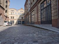 a cobblestone street near a building with a blue door and brick walls that lead up to the entrance