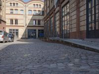 a cobblestone street near a building with a blue door and brick walls that lead up to the entrance