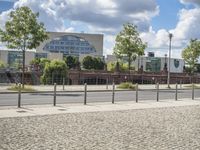 a fenced off street with some buildings behind it on a sunny day in the city