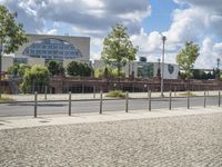 a fenced off street with some buildings behind it on a sunny day in the city