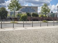 a fenced off street with some buildings behind it on a sunny day in the city