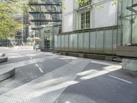 concrete benches in front of glass doors on a sidewalk on a sunny day in the city