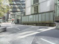 concrete benches in front of glass doors on a sidewalk on a sunny day in the city