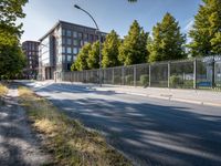 an empty street lined with a long building and many trees in the distance on a sunny day