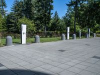 a public park with lots of concrete poles and trees in the background, with a paved area to the right