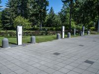 a public park with lots of concrete poles and trees in the background, with a paved area to the right