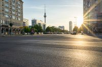 a busy street is lit up with the sun setting on the horizon in berlin, germany