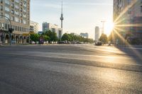 a busy street is lit up with the sun setting on the horizon in berlin, germany