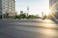 a busy street is lit up with the sun setting on the horizon in berlin, germany