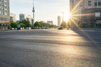 a busy street is lit up with the sun setting on the horizon in berlin, germany