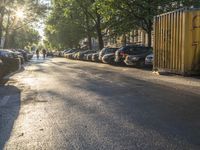 the sun shines on a street where cars and buildings are parked along a city road