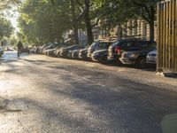 the sun shines on a street where cars and buildings are parked along a city road