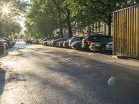 the sun shines on a street where cars and buildings are parked along a city road