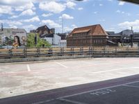 an empty parking lot on a sunny day, looking over buildings to a street corner with a bridge in front