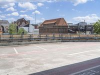 an empty parking lot on a sunny day, looking over buildings to a street corner with a bridge in front