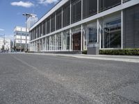 an empty street with buildings and people walking by it on a sunny day from the back