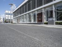 an empty street with buildings and people walking by it on a sunny day from the back