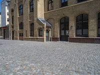 the sidewalk is paved with stones and has a bench in front of it, with no people inside