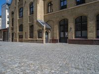 the sidewalk is paved with stones and has a bench in front of it, with no people inside