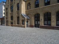 the sidewalk is paved with stones and has a bench in front of it, with no people inside