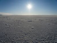 the sun shines in the sky above a snowy landscape, with footprints and footprints all across the vast expanse