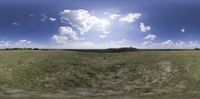 a view of a field with blue skies above it and clouds in the background of this image