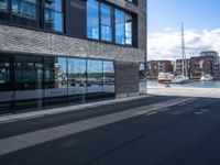 a bus parked by a building with boats in the harbor behind it next to it