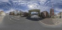 this is an 360 lens view of the street in front of some houses on a sunny day