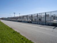 a chain link fence and a street on a sunny day at a large factory with no gates