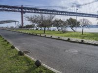 a street lined with black balls under a bridge over a body of water on a sunny day