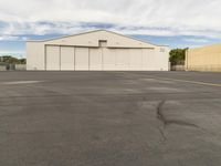 an empty parking lot in front of a building on a sunny day with clouds overhead