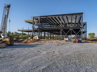 a picture of a building being built on a field near a forest in the background