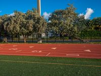 an image of a track in the middle of the day with a clock tower in the background