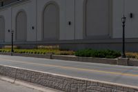 a man riding his skateboard down the road on a sidewalk near a building and grass area