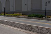 a man riding his skateboard down the road on a sidewalk near a building and grass area