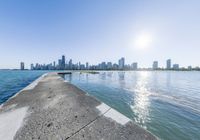 a large body of water sitting next to a city with tall buildings behind it,