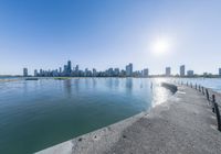 a large body of water sitting next to a city with tall buildings behind it,