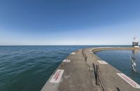 a pier with several steps leading to some water and a light tower in the background