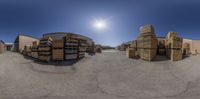 the spherical view shows multiple stacks and pallets in front of a building and the sun in the background