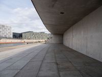 a view down a brick walkway towards city buildings by the water on a sunny day