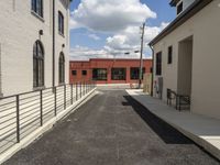 a paved street next to the front gate of a building and staircases on both sides