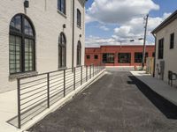 a paved street next to the front gate of a building and staircases on both sides