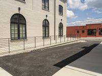 the road leads to a building with windows and black bars on the sidewalk to the side