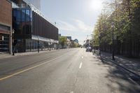 the sun shining on an empty street in an urban area that includes buildings and a bicycle