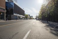 the sun shining on an empty street in an urban area that includes buildings and a bicycle