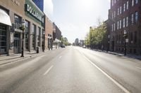 the sun shining on an empty street in an urban area that includes buildings and a bicycle